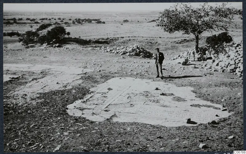 Mosaic floor at the ruins of the Temple of Aphrodite, Kouklia, with a man in a suit standing beside it.