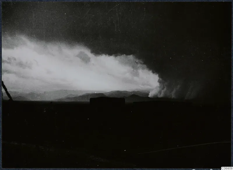 Storm clouds over distant hills, with a bright cloud bank to the left and a dark sky above