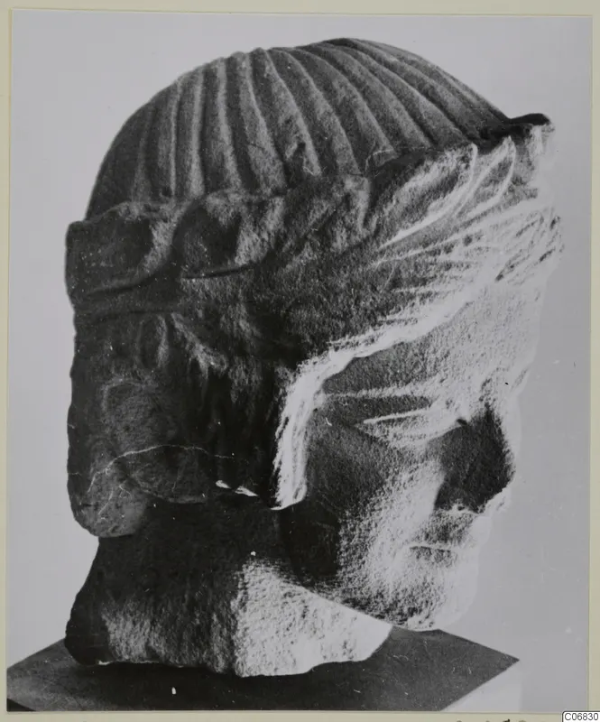 Limestone sculpture head from Mersinaki, shown in side view on a dark stand.
