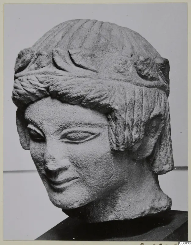 Carved limestone head of a figure with ridged hair, a band across the forehead, and a slight smile, from Mersinaki