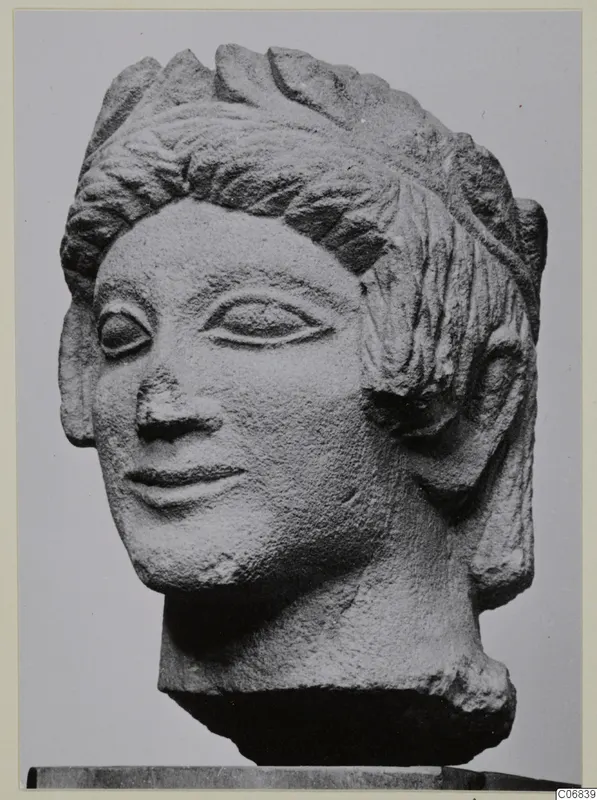 Limestone head from Mersinaki with layered hair and a faint smile, photographed against a plain grey background