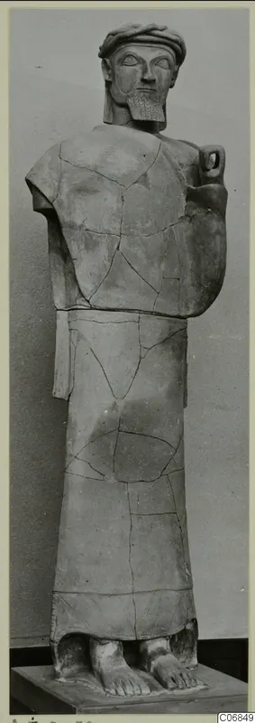 Terracotta statue of a standing bearded man in a long garment, reassembled from broken pieces