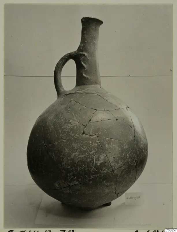 Pottery Red Polished I jug from Lapithos, with a long neck, single loop handle and repaired cracks on the body