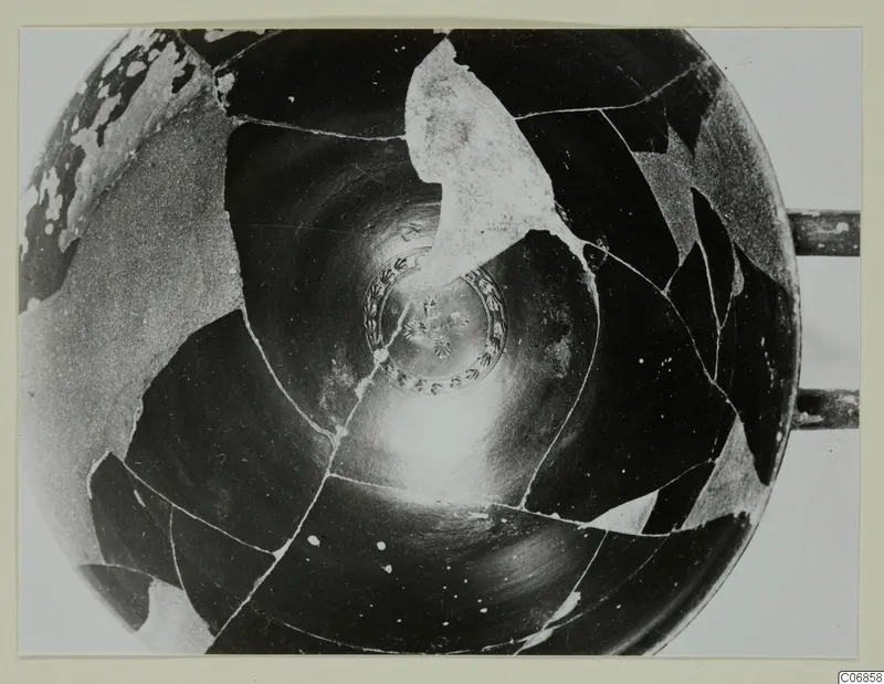 Interior of a black-glazed bowl reassembled from sherds, with a patterned medallion at the centre