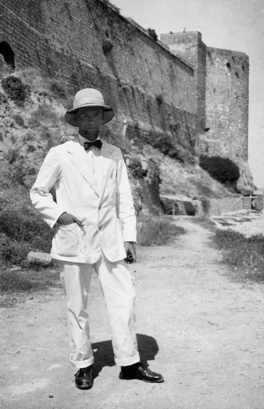 Alfred Westholm in a white suit and pith helmet beside the fortress wall at Kyrenia