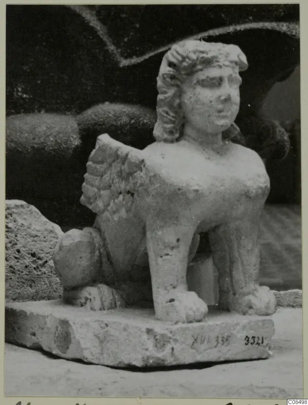 Stone sculpture of a winged creature with a human face and curly hair, standing on a rectangular base, from Soli