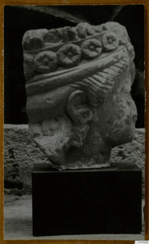 Carved stone architectural fragment with a row of round discs with star-like centres, on a dark stand