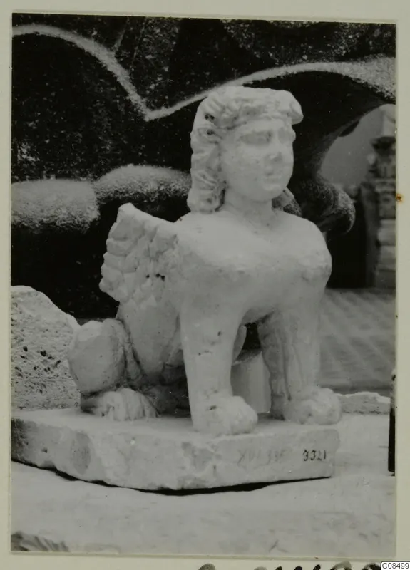 Pale stone statue of a seated winged figure with a human-looking head, on a rectangular base, from Soli