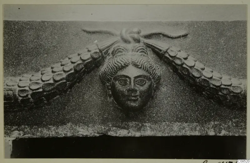 Carved stone relief of a woman's face framed by scalloped forms, find from North Africa