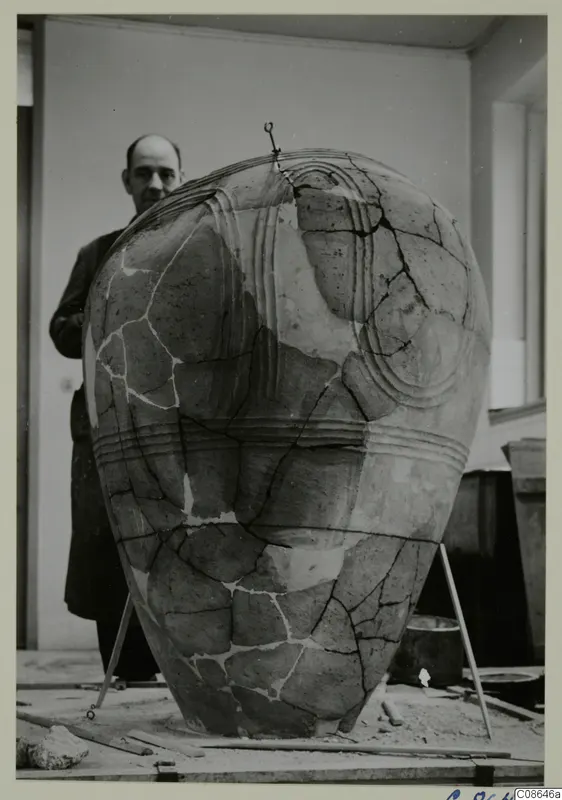 Large reconstructed pottery pithos with raised ridged bands, with a man in a dark coat standing behind it