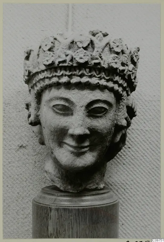 Limestone head fragment from Vouni, with a high headdress of raised leaf-like ornament and a smiling face
