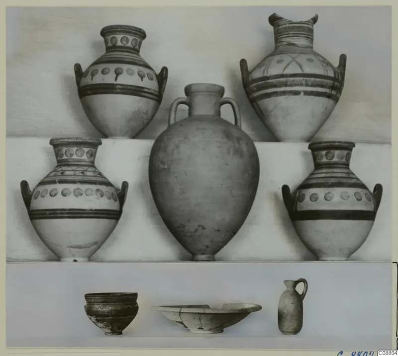 Group of nine pottery vessels from Marion Tomb 71: four painted handled jars, a plain jar and small bowls and a juglet, arranged on a shelf