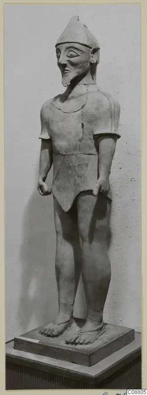 Terracotta statue of a standing male figure with a pointed cap and beard, on a rectangular wooden base