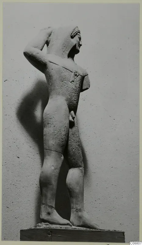 Limestone statue of a standing nude male from Kition, one arm raised to the head.