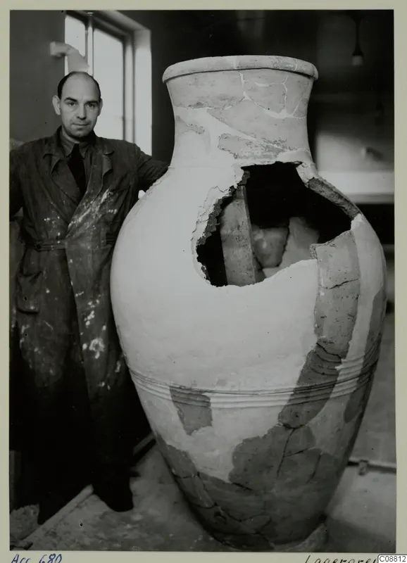 Large reconstructed pottery jar with a man in a paint-spattered coat standing beside it