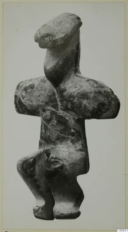 Stone figurine from Petra tou Limniti with arms folded across the chest, photographed against a plain background.