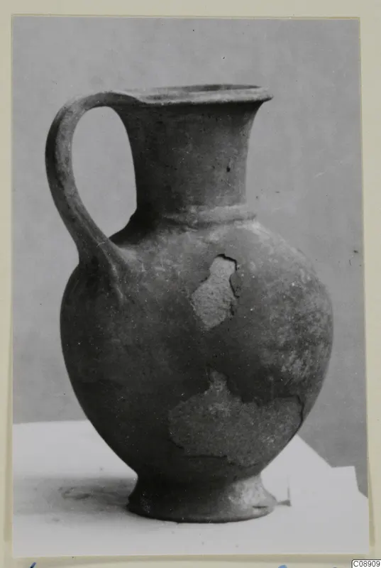 Pottery jug in Base-Ring Ware with a single loop handle, a flared neck and a ring foot