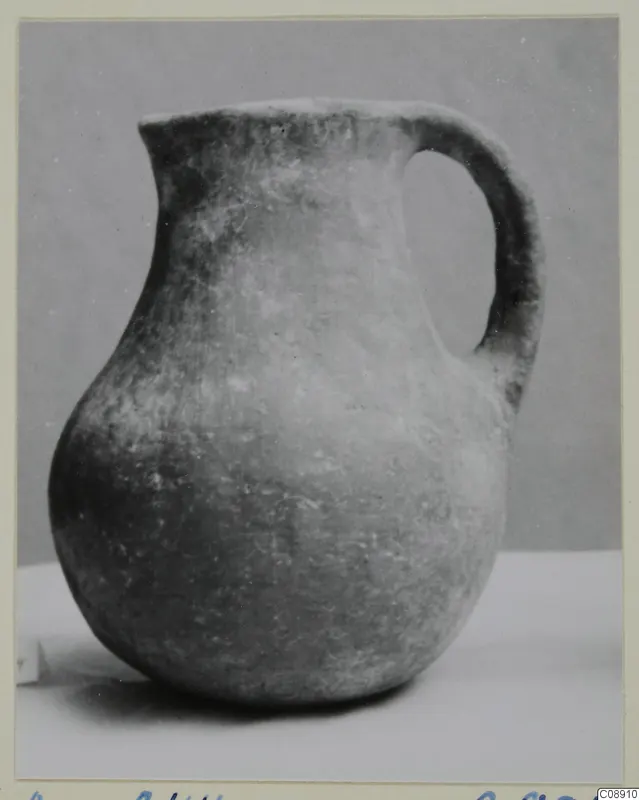 Pottery Monochrome Ware jug with a single strap handle, shown on a white surface