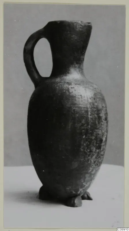 Pottery jug with one loop handle, Pottery Red Lustrous Ware, photographed against a grey backdrop