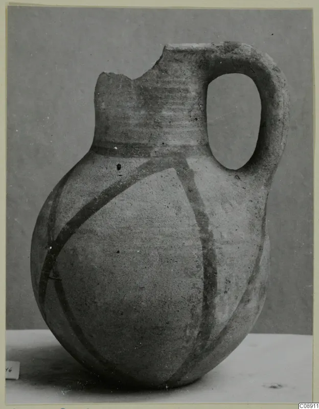White Painted wheel-made jug with a broken rim, a single loop handle and dark painted bands on the body