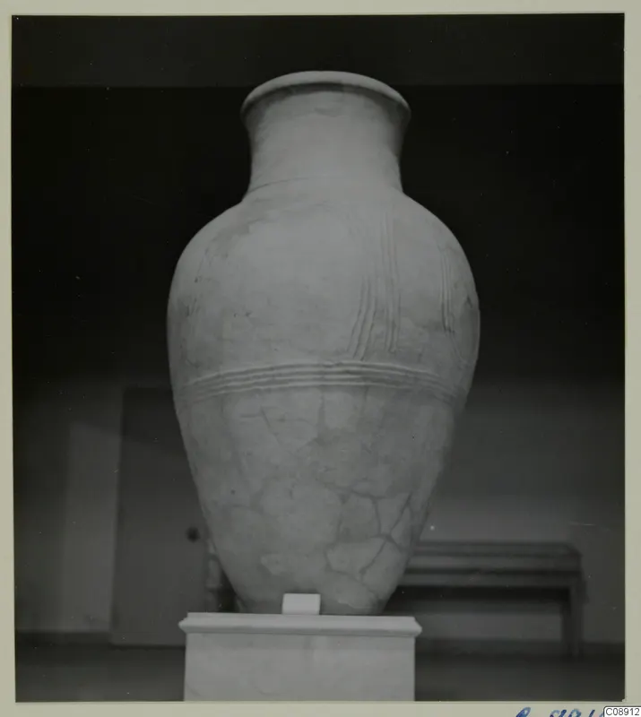 Large pottery pithos ware jar with raised ridged bands, standing on a white pedestal