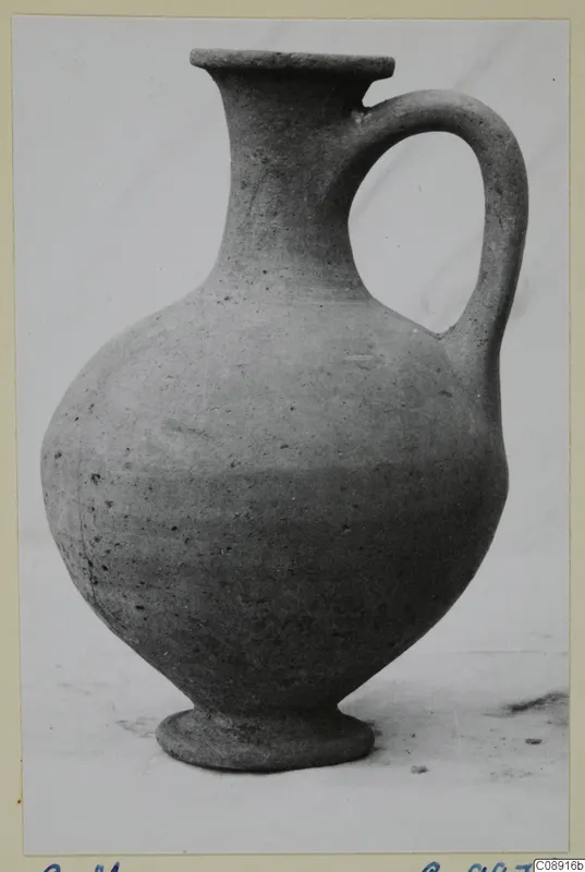 Plain pottery jug with a single loop handle, photographed on a pale background