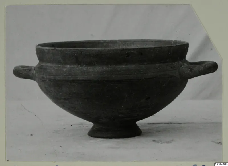 Footed bowl with two horizontal handles and a dark, smooth surface.
