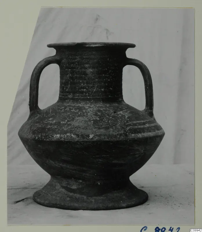 Two-handled pottery vessel with a flared rim, photographed against a pale backdrop