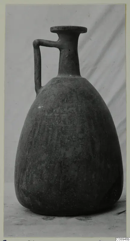 Jug with a single strap handle and a flat disc rim, photographed against a grey draped cloth