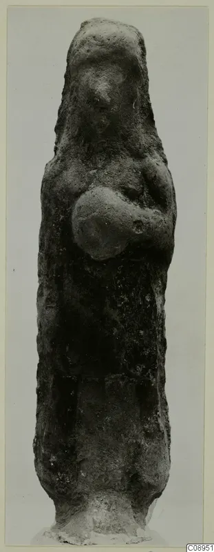 Standing terracotta figurine with arms bent across the chest, seen from the front against a grey backdrop.
