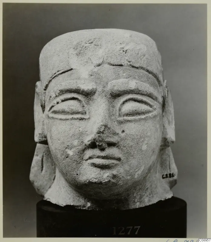 Limestone sculpture head, Neo-Cypriote, seen from the front on a dark stand