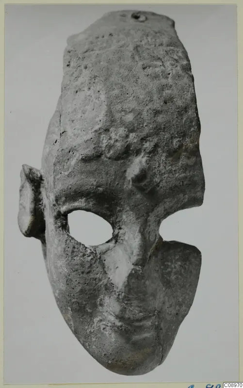 Terracotta face-shaped object with a large oval eye opening, a small ear on one side and a suspension hole at the top