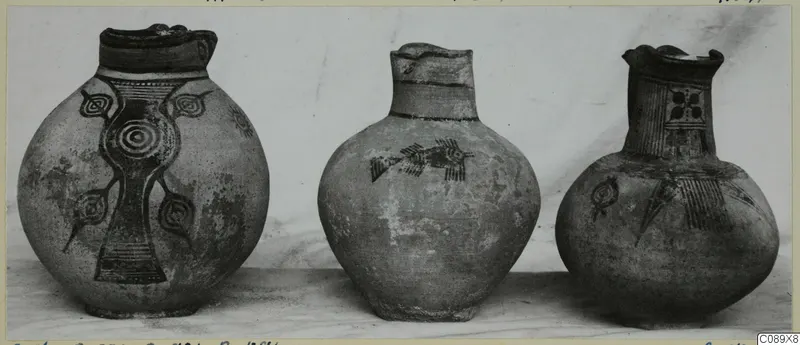 Three painted jugs with dark geometric decoration, photographed side by side against a pale background
