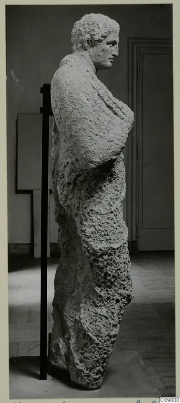Limestone statue of a standing figure from Mersinaki, turned in profile and held on a black support rod