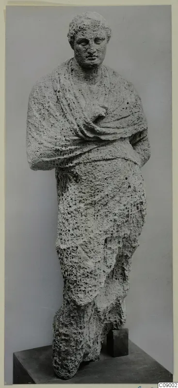 Standing draped statue from Mersinaki, carved in pitted pale stone, with a cloth mantle over the shoulders and arms
