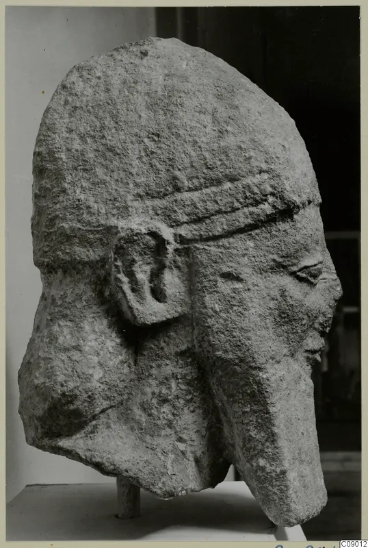 Limestone head of a figure wearing a banded cap, photographed in three-quarter view from the side