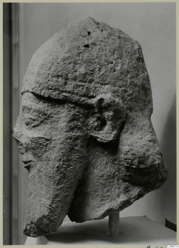 Weathered limestone head from Kition, shown in side view on a white pedestal