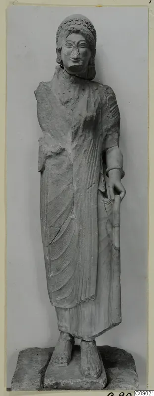 Limestone statue of a standing figure with a curled headdress, holding a tall rod, from Vouni.