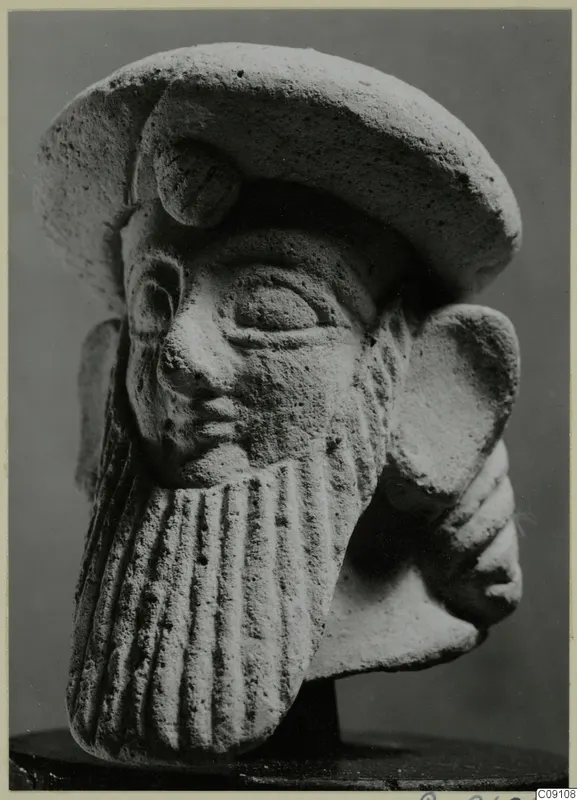 Terracotta Neo-Cypriote head of a bearded figure wearing a flat cap, shown on a dark stand