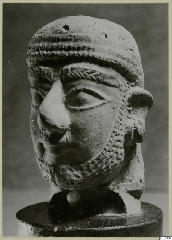 Terracotta head of a bearded man with a ridged band across the forehead, on a wooden stand