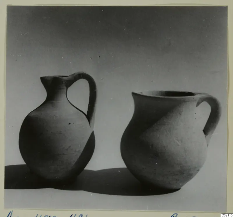 Two plain pottery vessels with handles, standing side by side