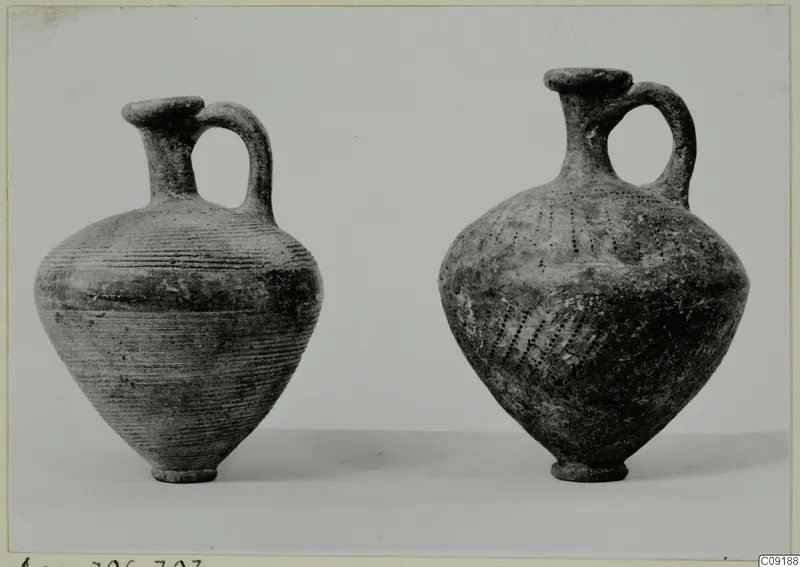 Two handled juglets with single loop handles, one with horizontal grooves and one with dotted decoration