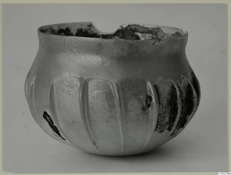 Blown glass vessel with vertical ribs and a broken, uneven rim