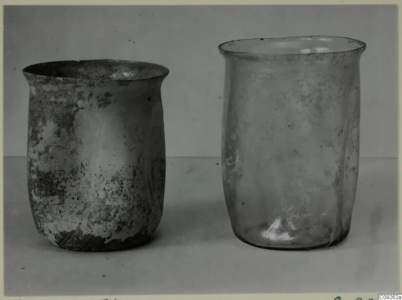 Two blown glass beakers standing side by side on a plain surface.