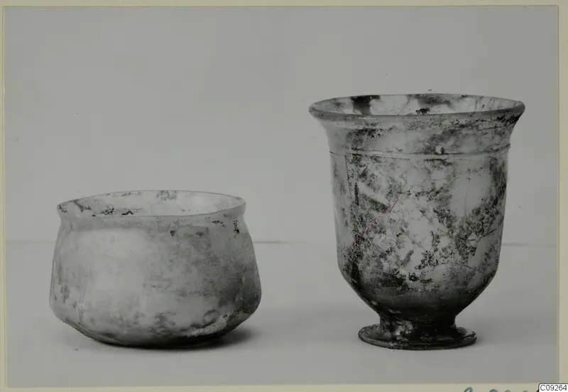 Two blown glass vessels: a squat jar on the left and a footed beaker with a flared rim on the right