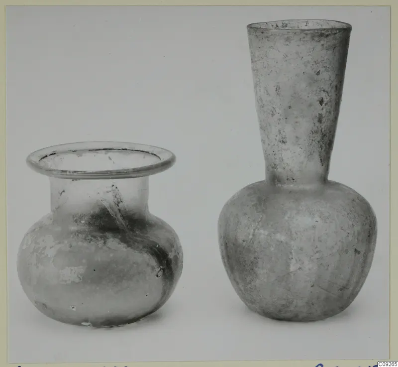 Two blown glass vessels side by side: a squat jar with a flared rim and a flask with a tall funnel neck