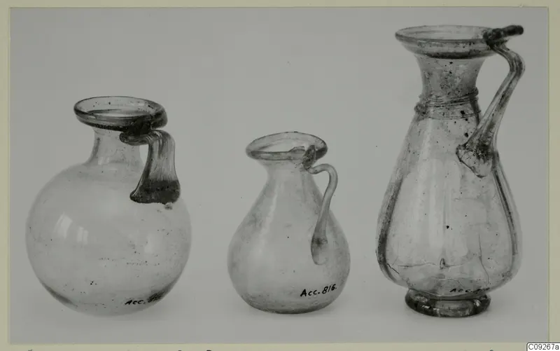Three blown glass jugs with handles, one globular, one small and pear-shaped, one tall with a ringed neck
