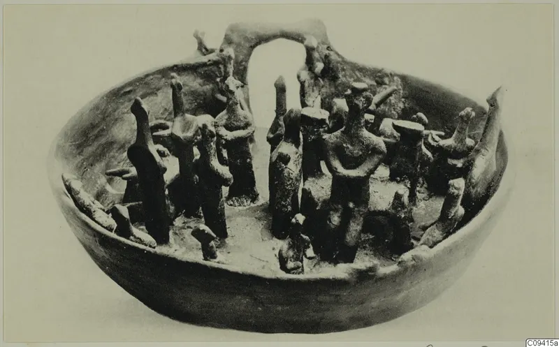 Terracotta bowl with an arched element at the back and many small standing figurines around its rim and inside.