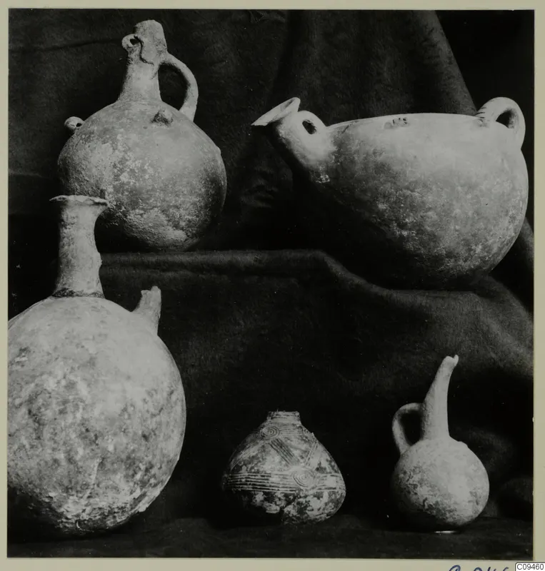 Five pottery vessels of different shapes arranged on dark draped cloth.