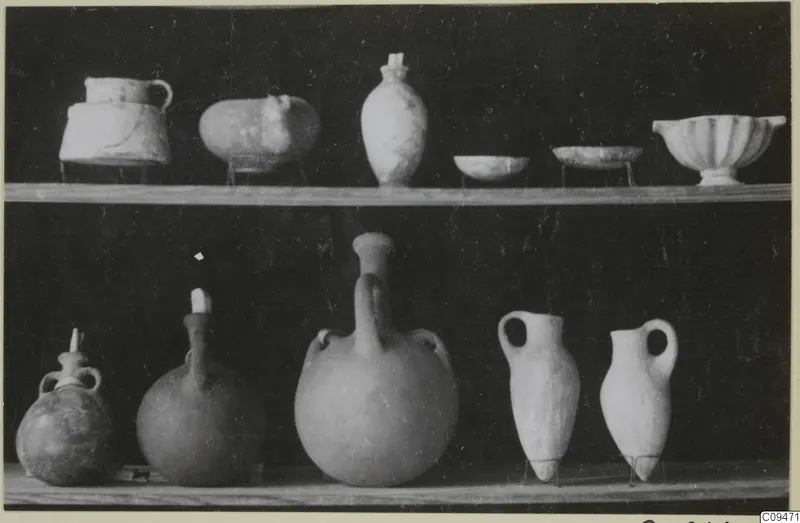Pots and bowls displayed on two wooden shelves against a dark background